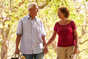 man and woman holding hands walking through the park